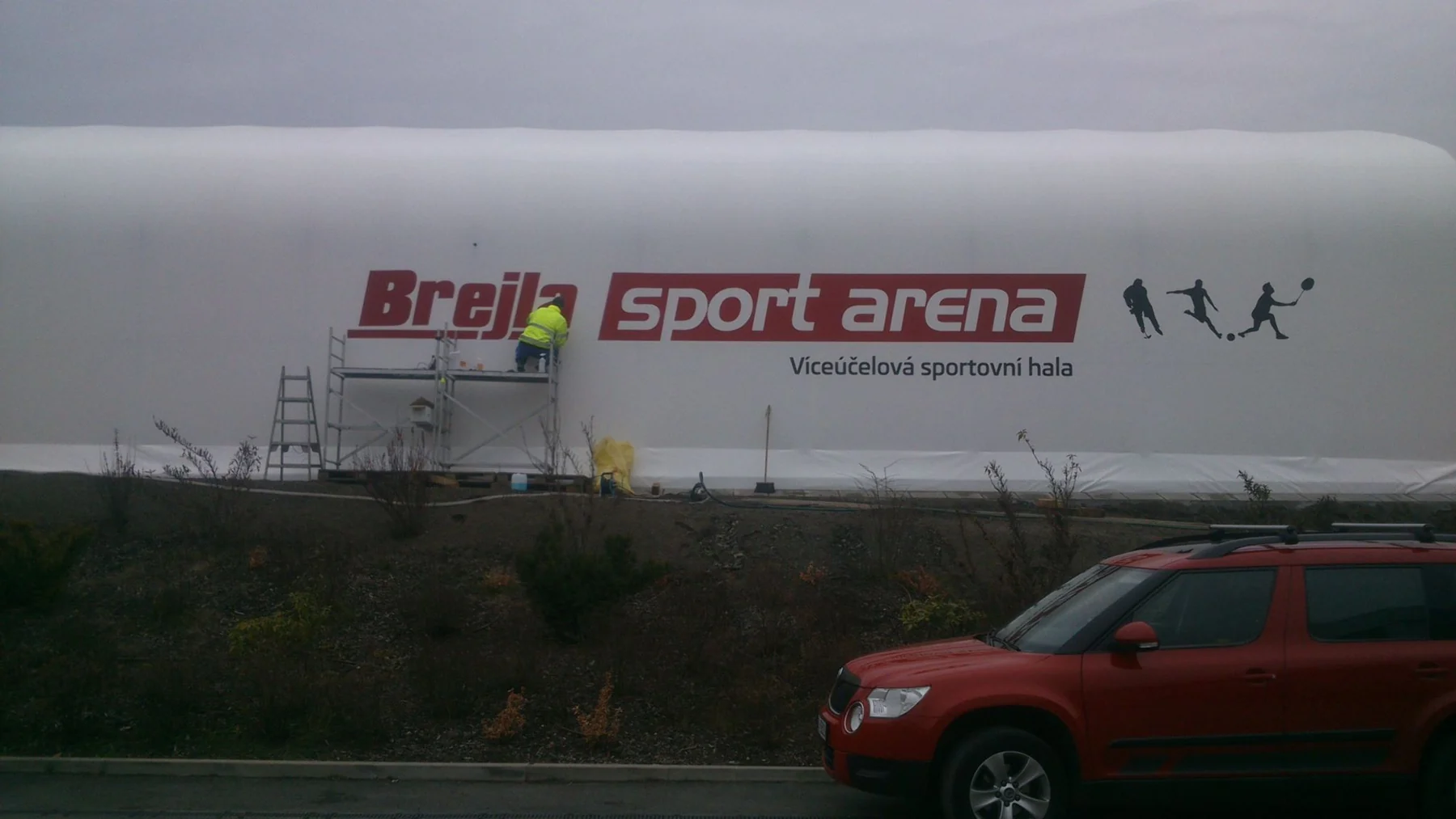 Montáž velkého nápisu sportarena na bílou stěnu haly