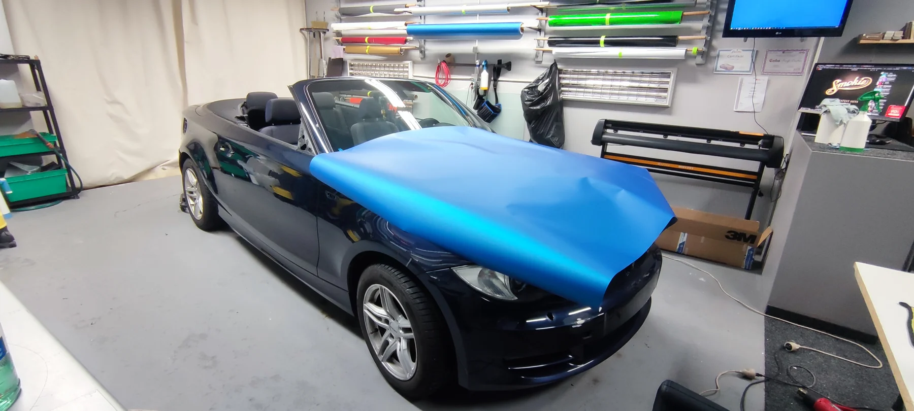 Modrá fólie položená na kapotě původně tmavého BMW