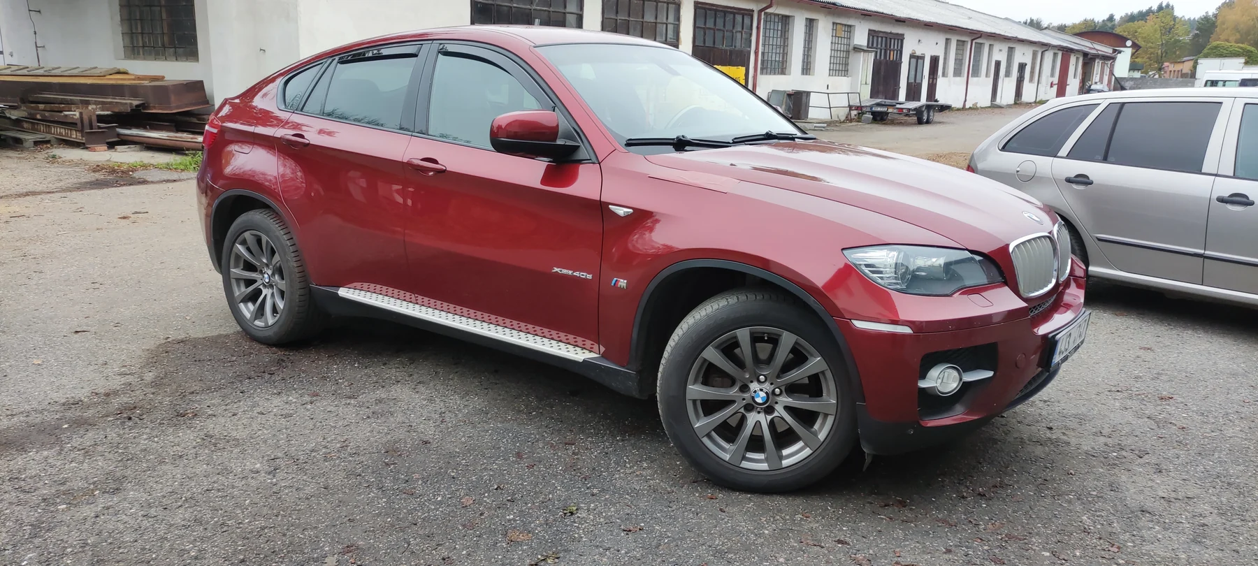 BMW X6 v původním tmavším červeném provedení venku před dílnou