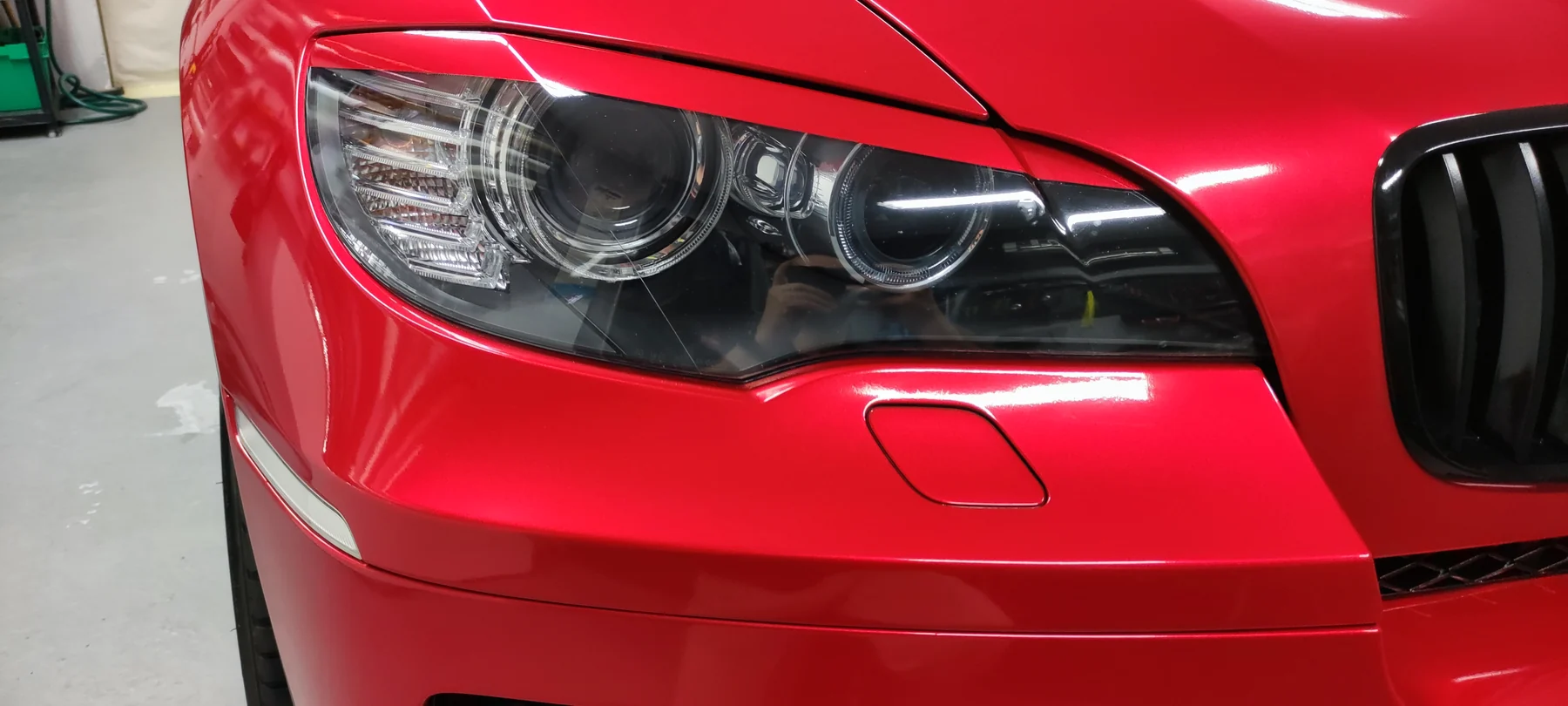 Detail lesklého červeného polepu kolem předního světla BMW X6