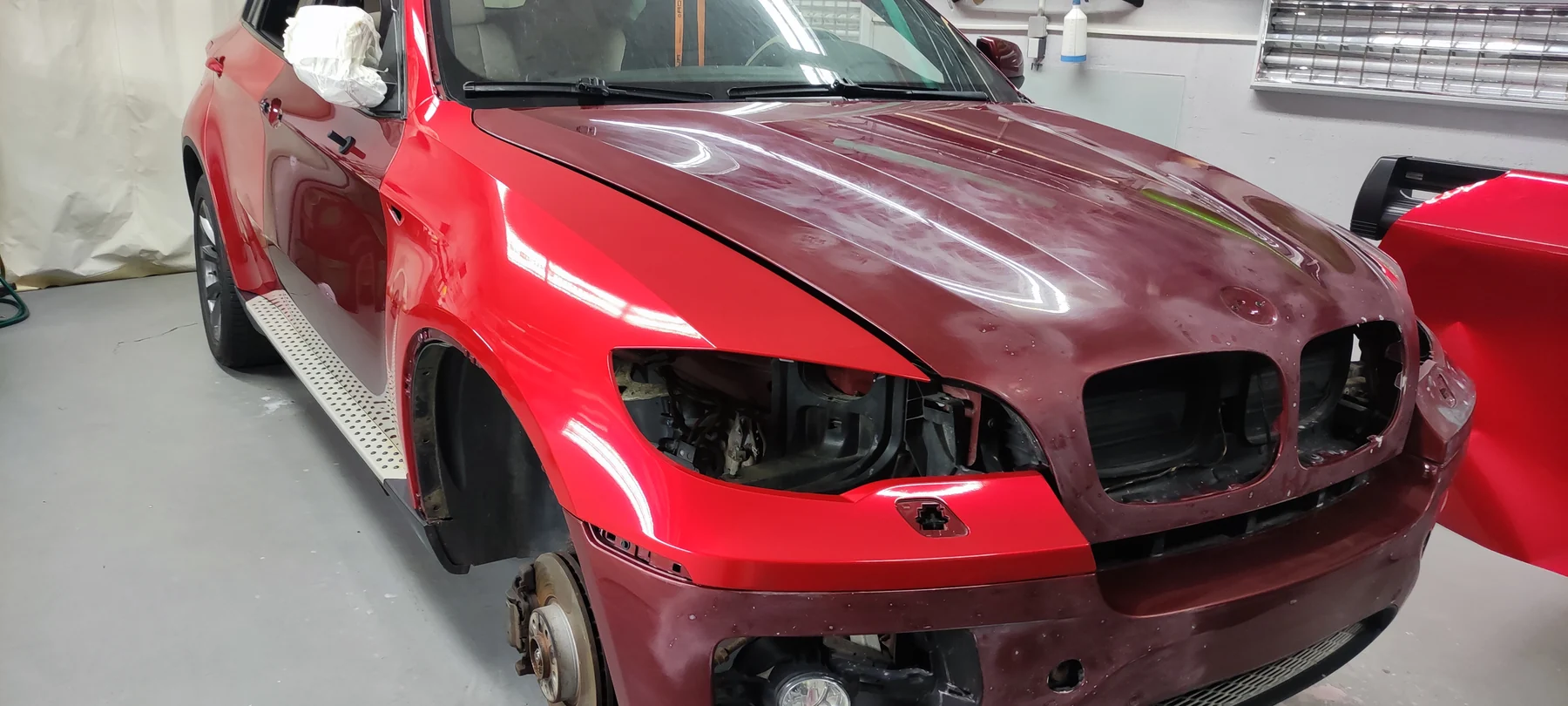 BMW X6 během polepu s původní kapotou a nově červenými blatníky