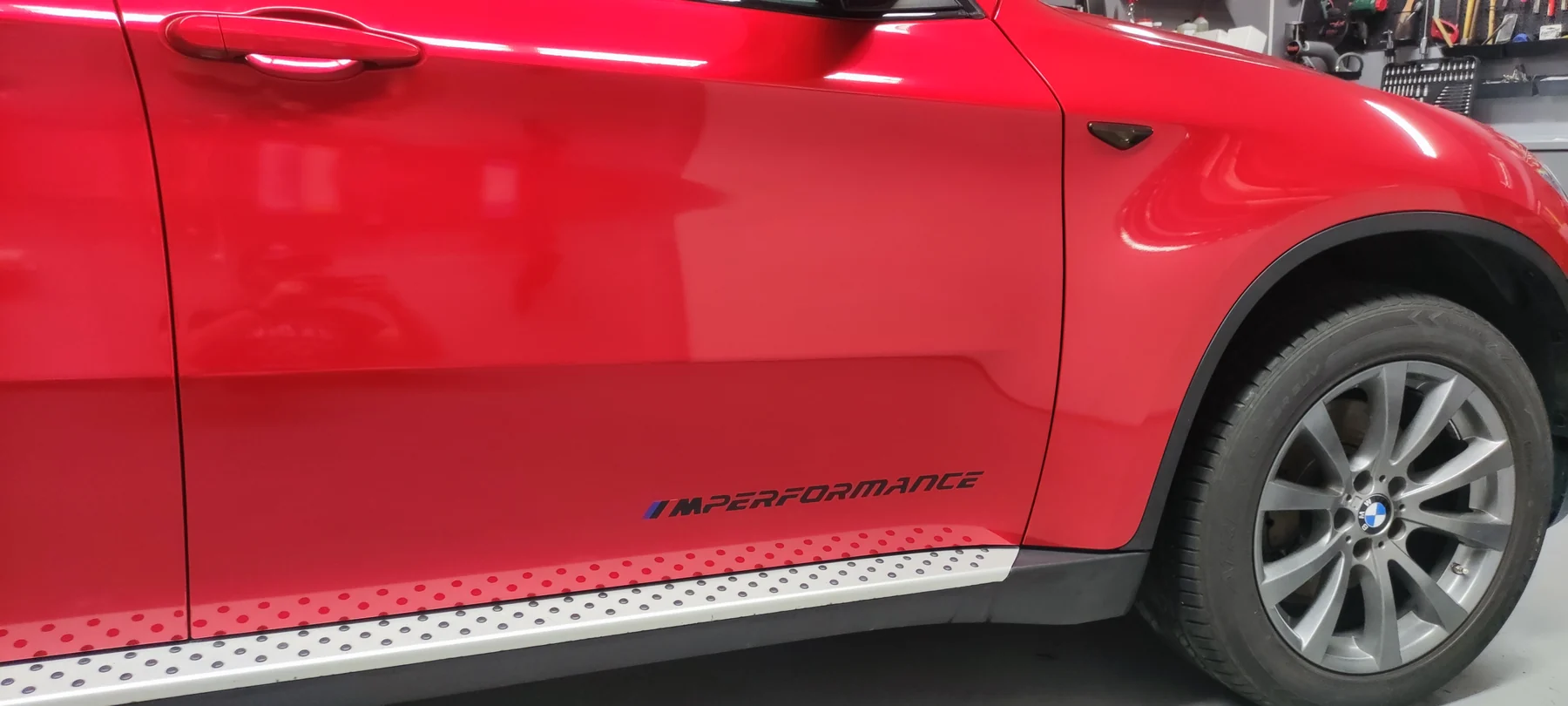 Červené boční dveře BMW X6 s malým černým nápisem u prahu