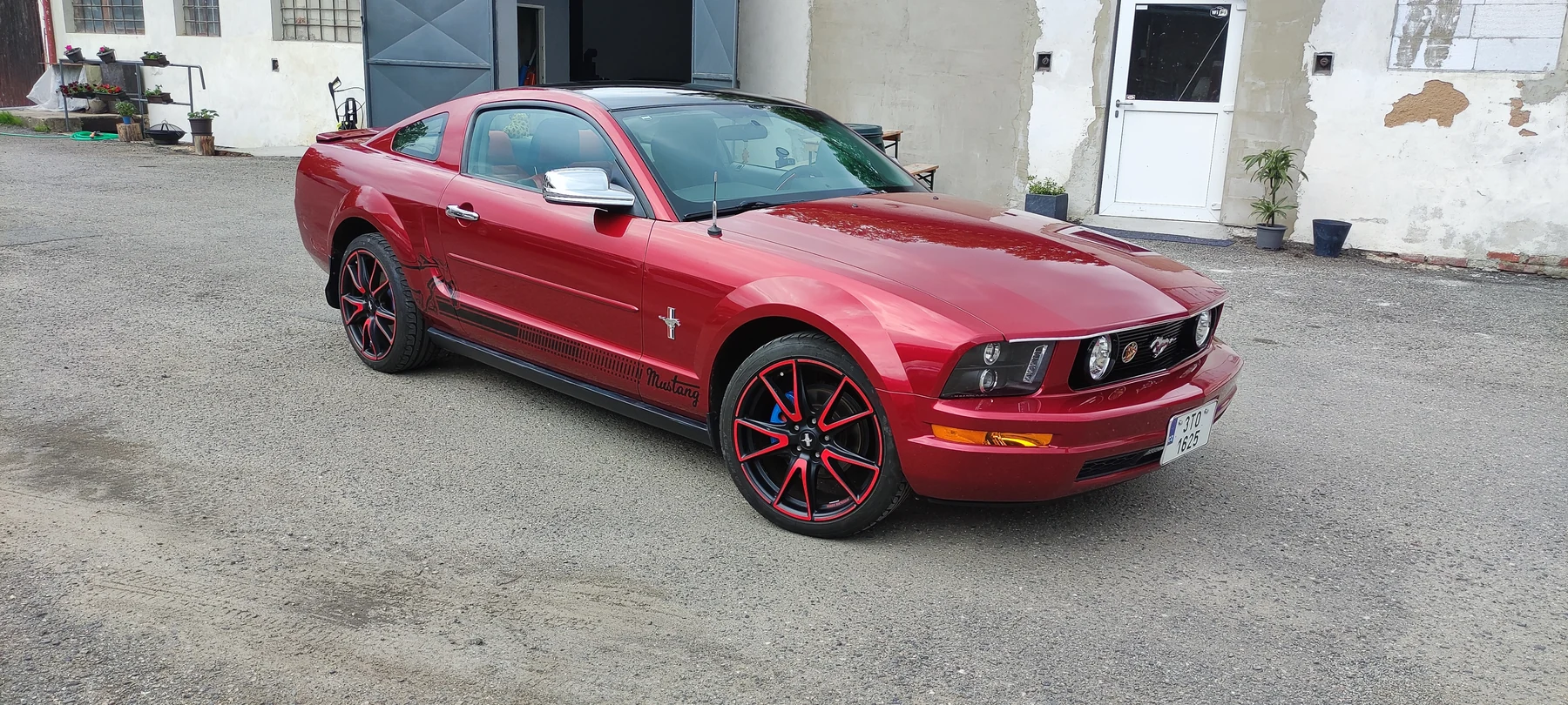 Červený Ford Mustang s černými bočními pruhy zepředu a z boku