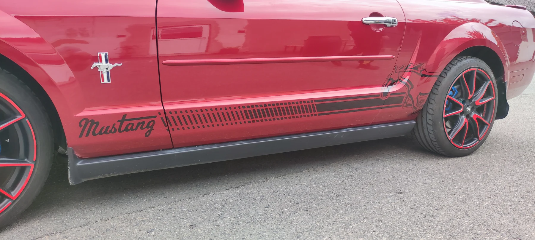 Detail černého nápisu Mustang a pruhů na červených dveřích