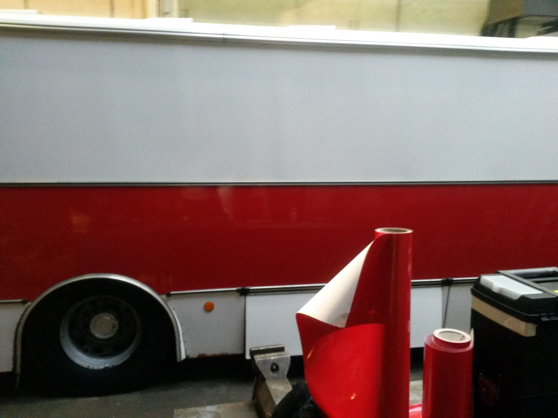 Červený pás na boku autobusu s připraveným materiálem v popředí