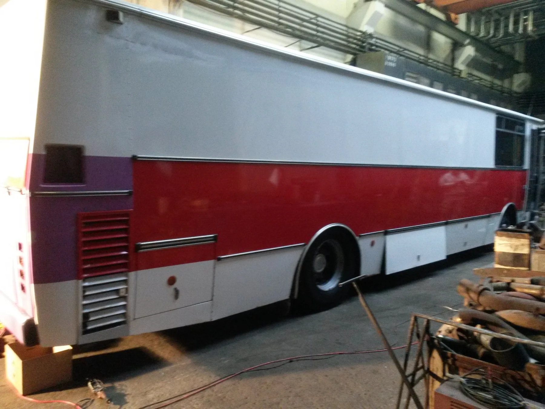 Bílý autobus s červeným bočním pásem při pohledu zezadu v hale
