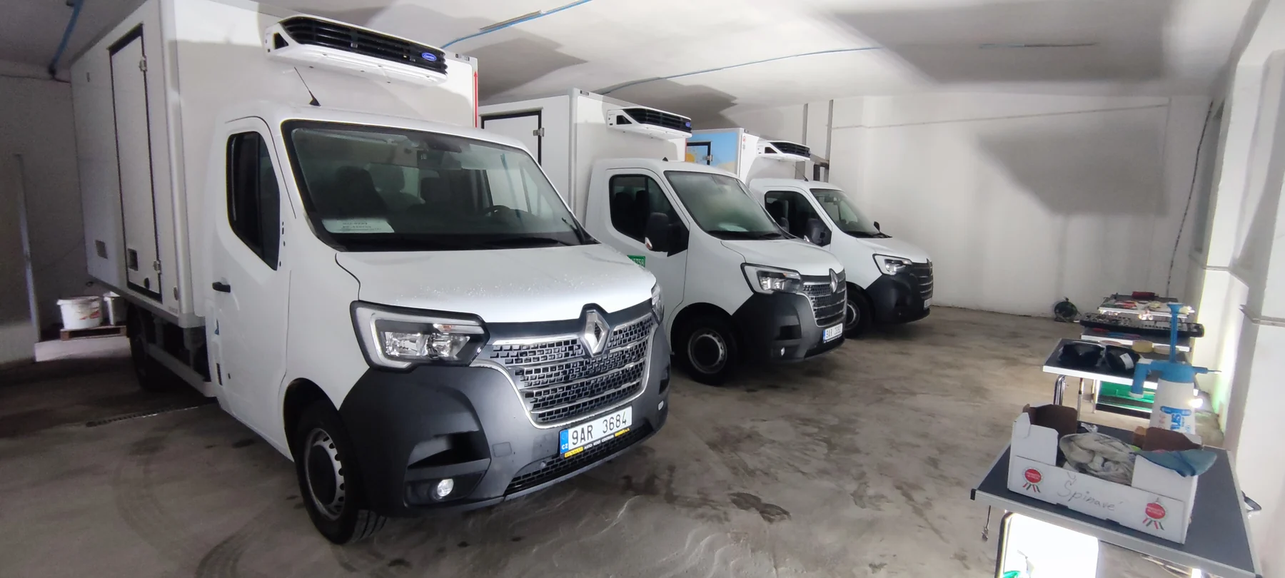 Několik bílých rozvozových Renaultů před dokončením firemního označení