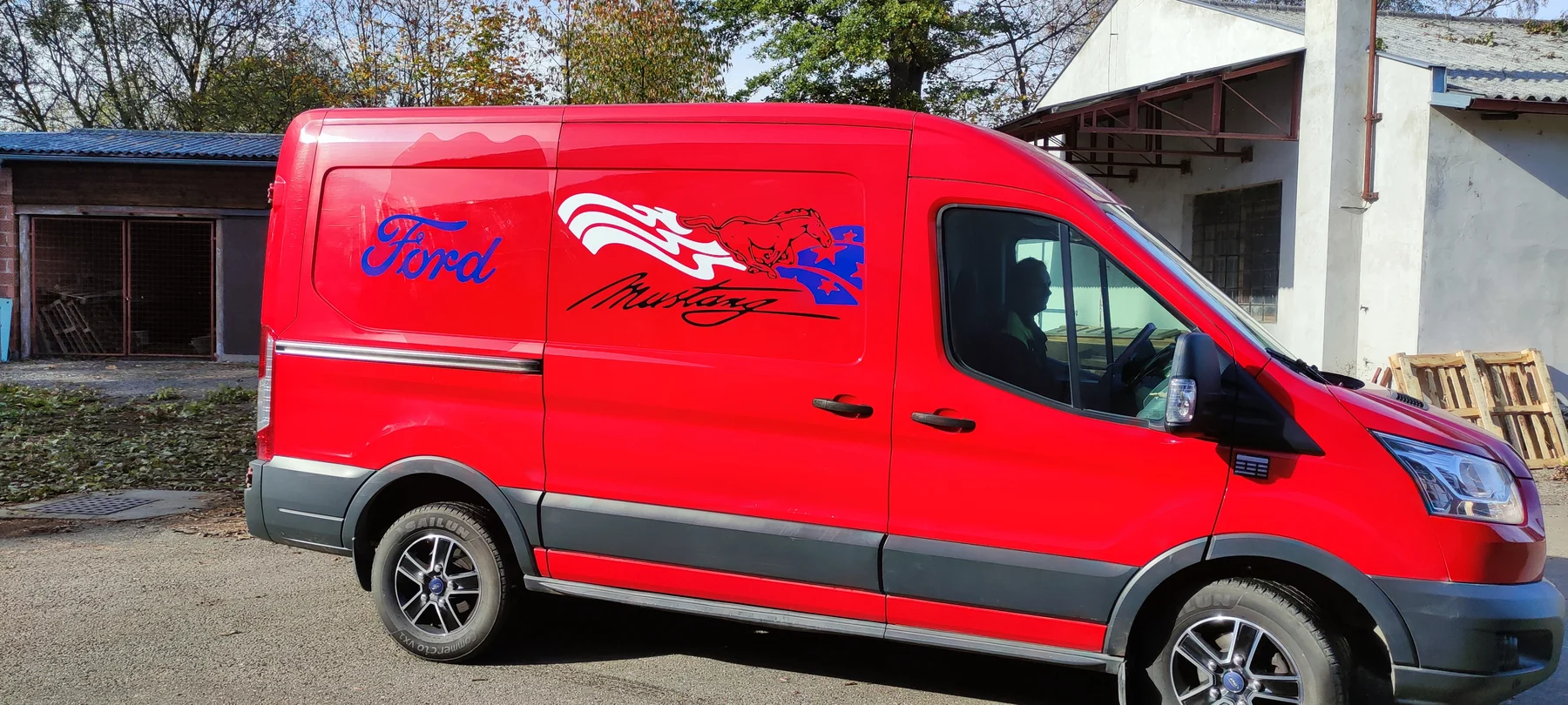 Červená dodávka Ford s bílým, modrým a černým motivem koně na boku