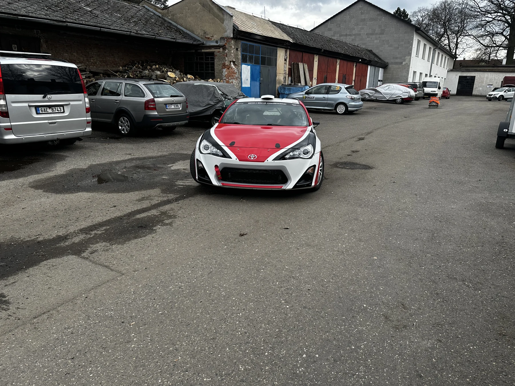 Červenobílé sportovní kupé po dokončení polepu před dílnou