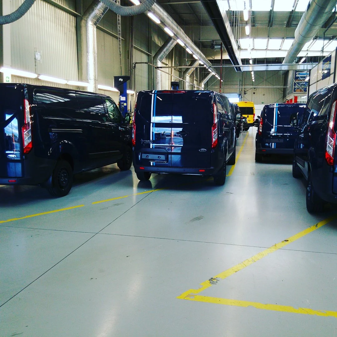 Řada modrých dodávek Ford zachycená zezadu