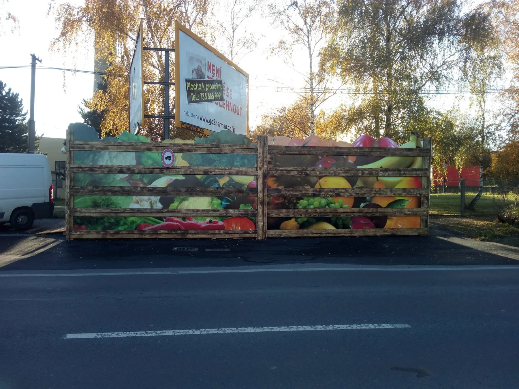 Dlouhá boční stěna stánku s velkými motivy čerstvého ovoce a zeleniny