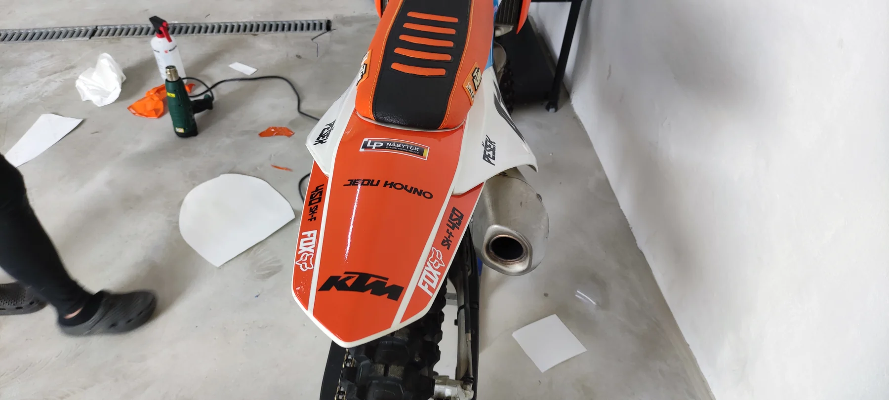 Detail oranžovobílého zadního blatníku KTM s nápisy
