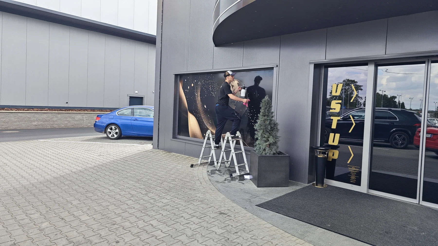 Pracovník při aplikaci reklamního motivu na výlohu