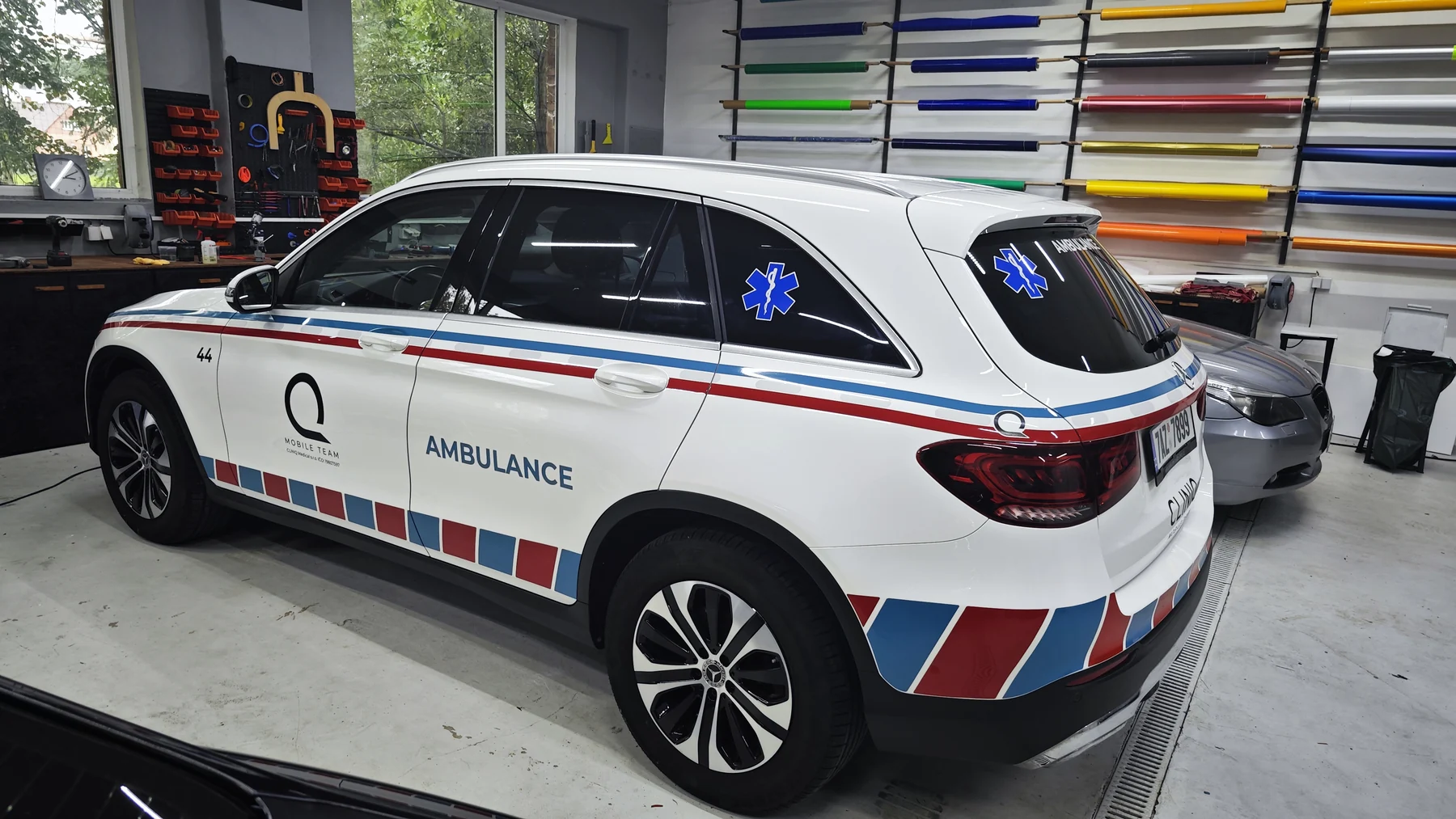 Mercedes CLINIQ zezadu a z boku s modrými symboly