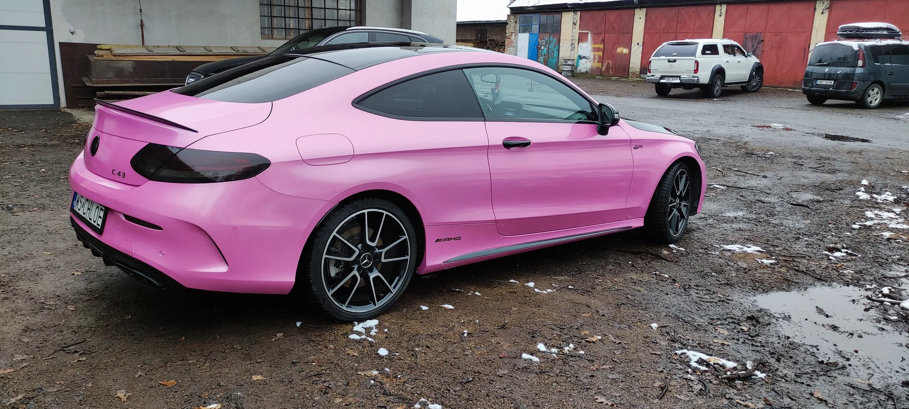 Pravý bok a záď růžového Mercedesu kupé před dílnou