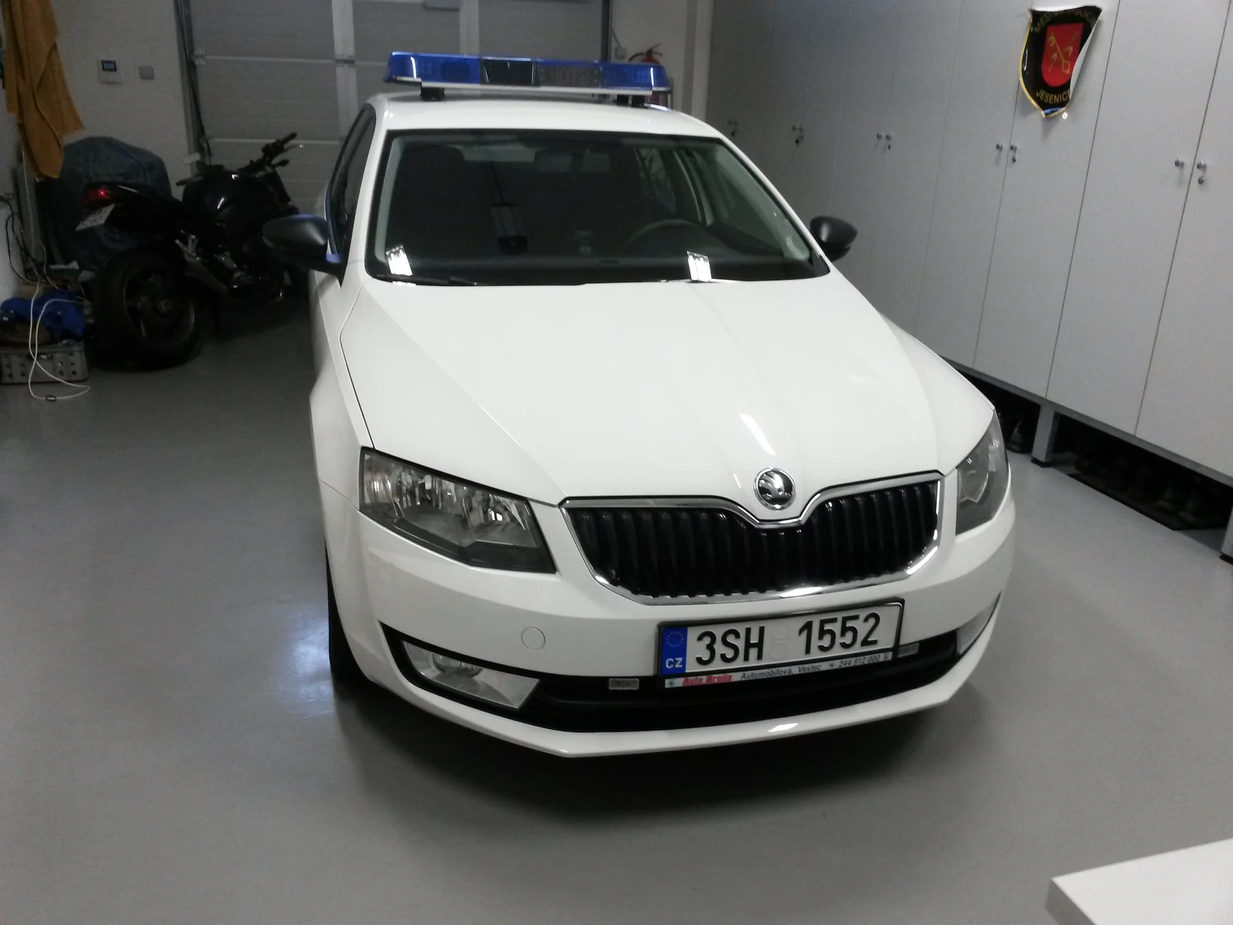 Bílá Octavia kombi se střešním majákem před aplikací označení