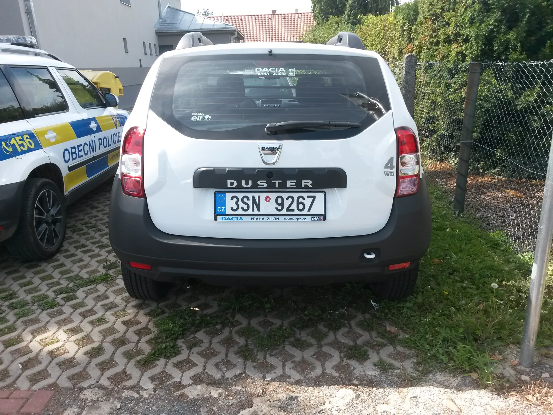 Bílý Dacia Duster před žlutomodrým policejním polepem