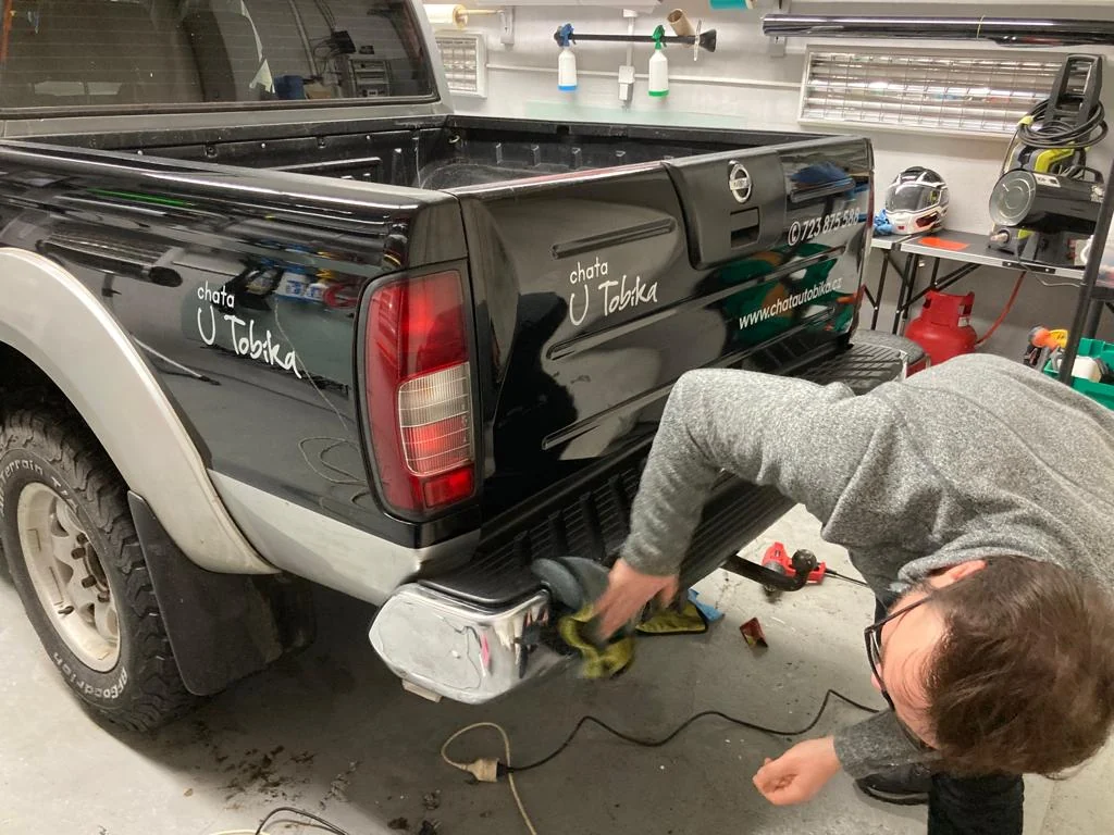 Nissan Navara zezadu a z boku s lesním motivem a tmavou zádí