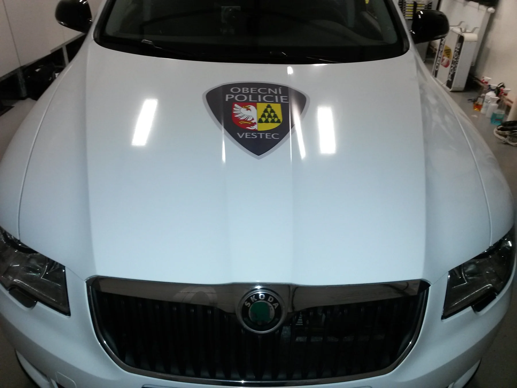 Znak Obecní policie Vestec na bílé kapotě Škody Superb