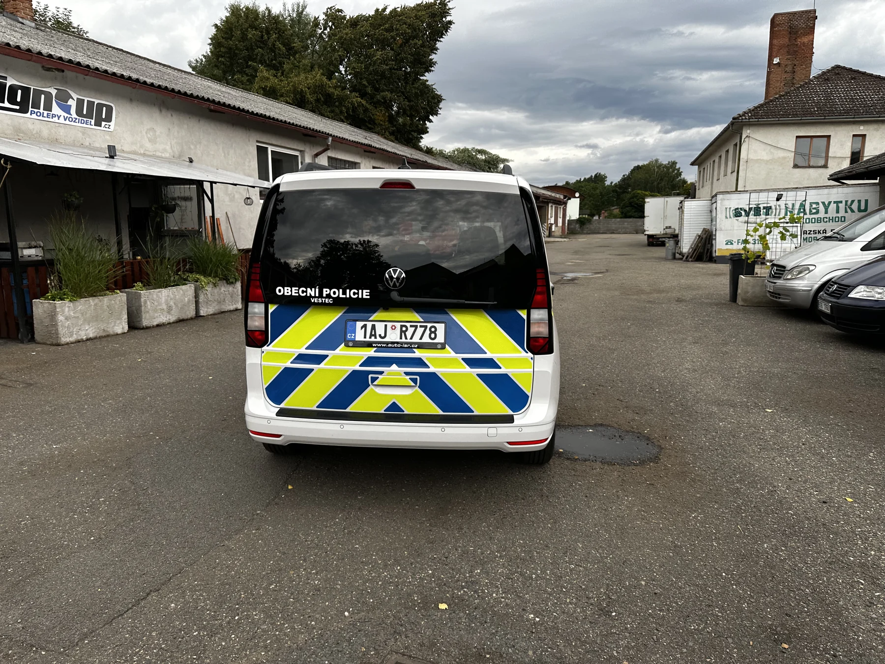 Zadní dveře Volkswagenu Caddy Obecní policie Vestec s modrými a žlutými šikmými pruhy