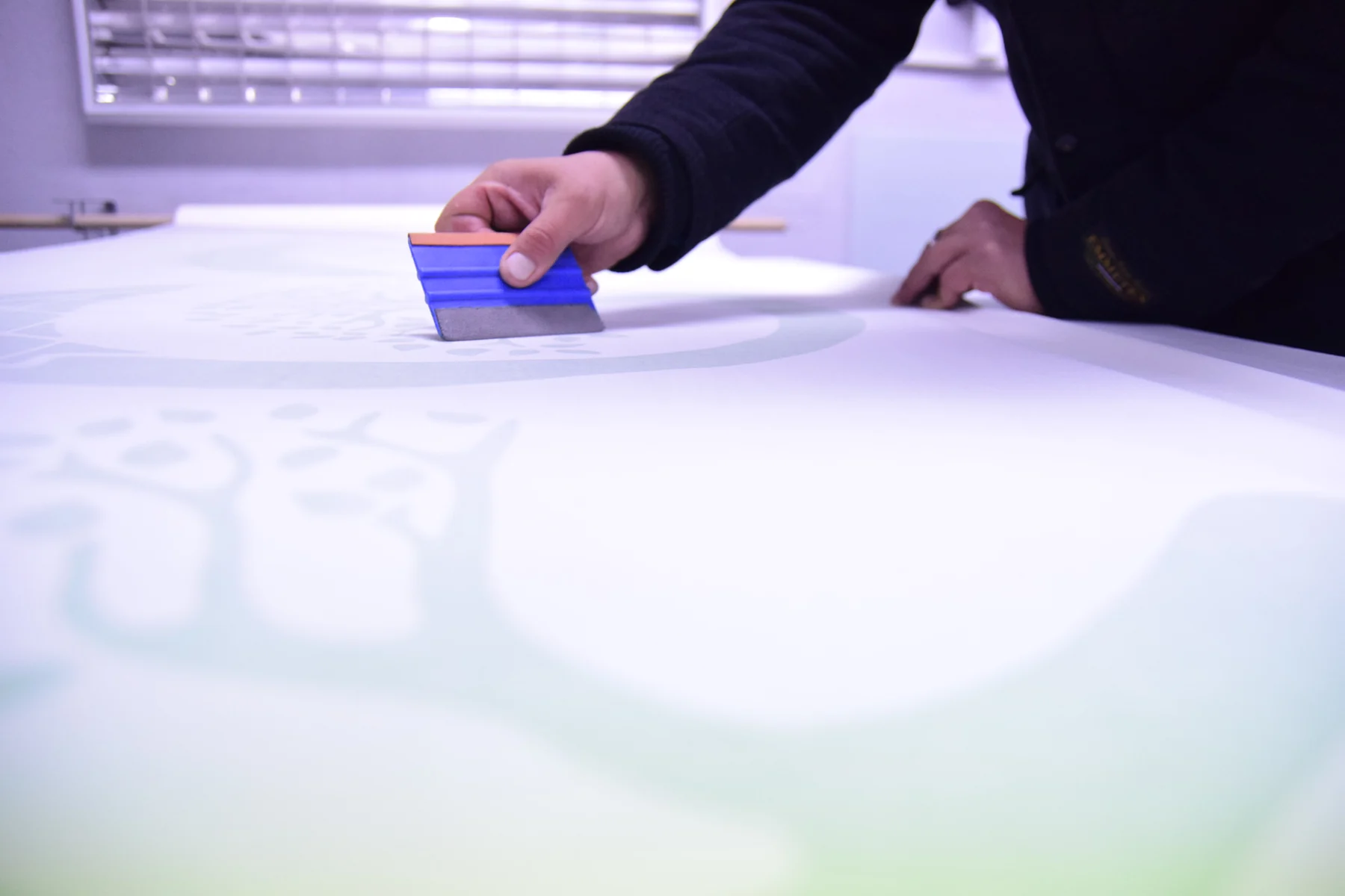 Detail práce stěrkou při přípravě velké grafiky ELEGreen v dílně
