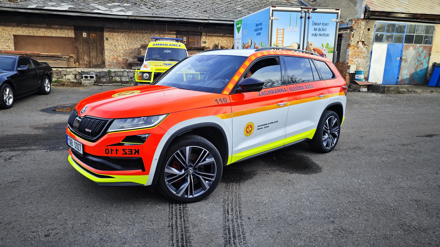 Bílé SUV Záchranné služby ASČR s oranžovočerveným a žlutým polepem zepředu a z boku