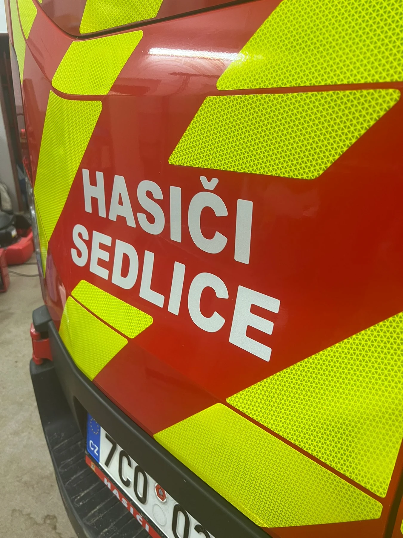 Detail žlutých dílů a bílého nápisu Hasiči Sedlice na červených zadních dveřích