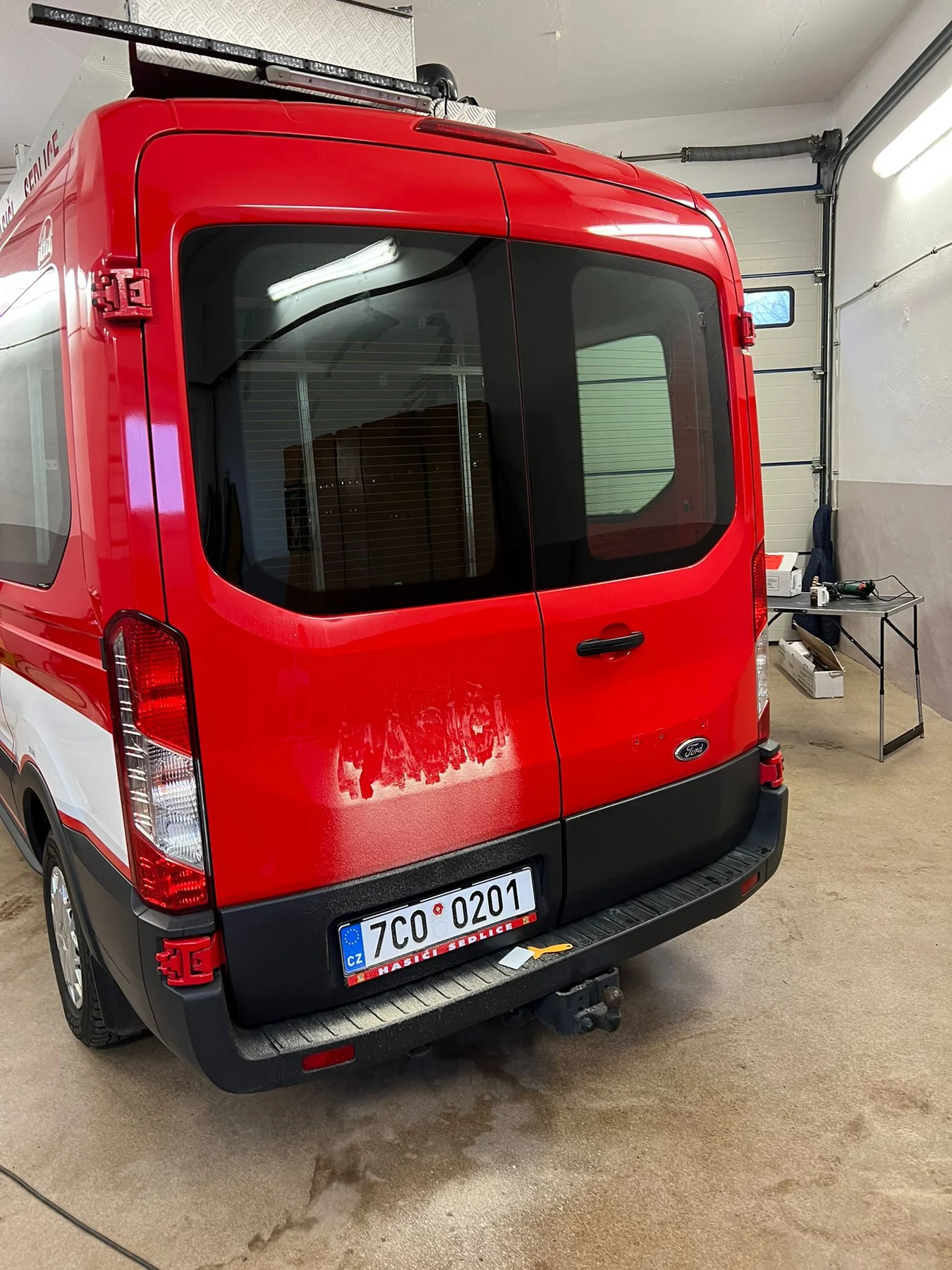 Zadní dveře červeného Fordu Transit Hasiči Sedlice před aplikací nového šrafovaného polepu