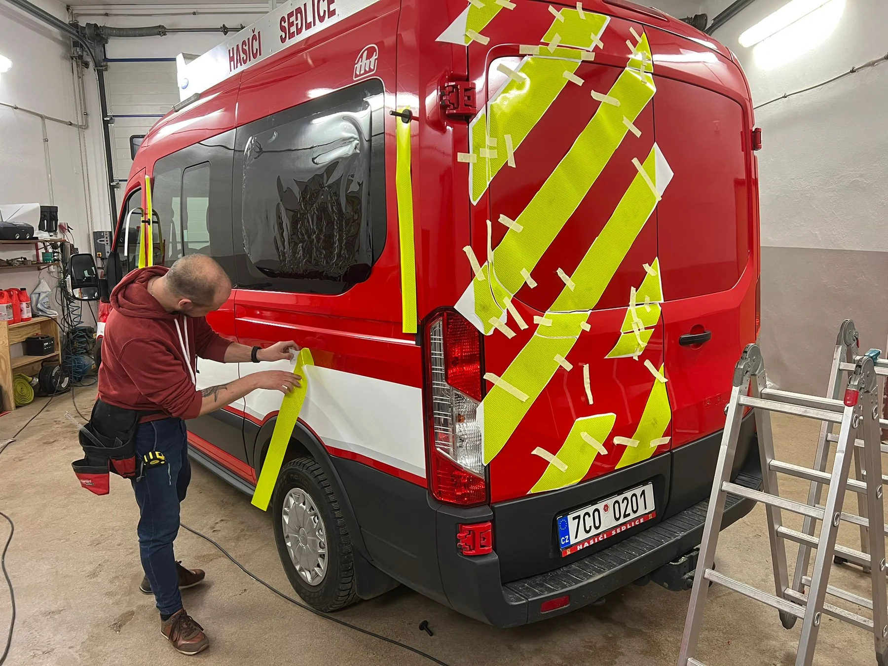 Aplikace žlutého polepu na Ford Transit Hasiči Sedlice, jednotlivé díly na zadních dveřích přichycené pomocnou páskou