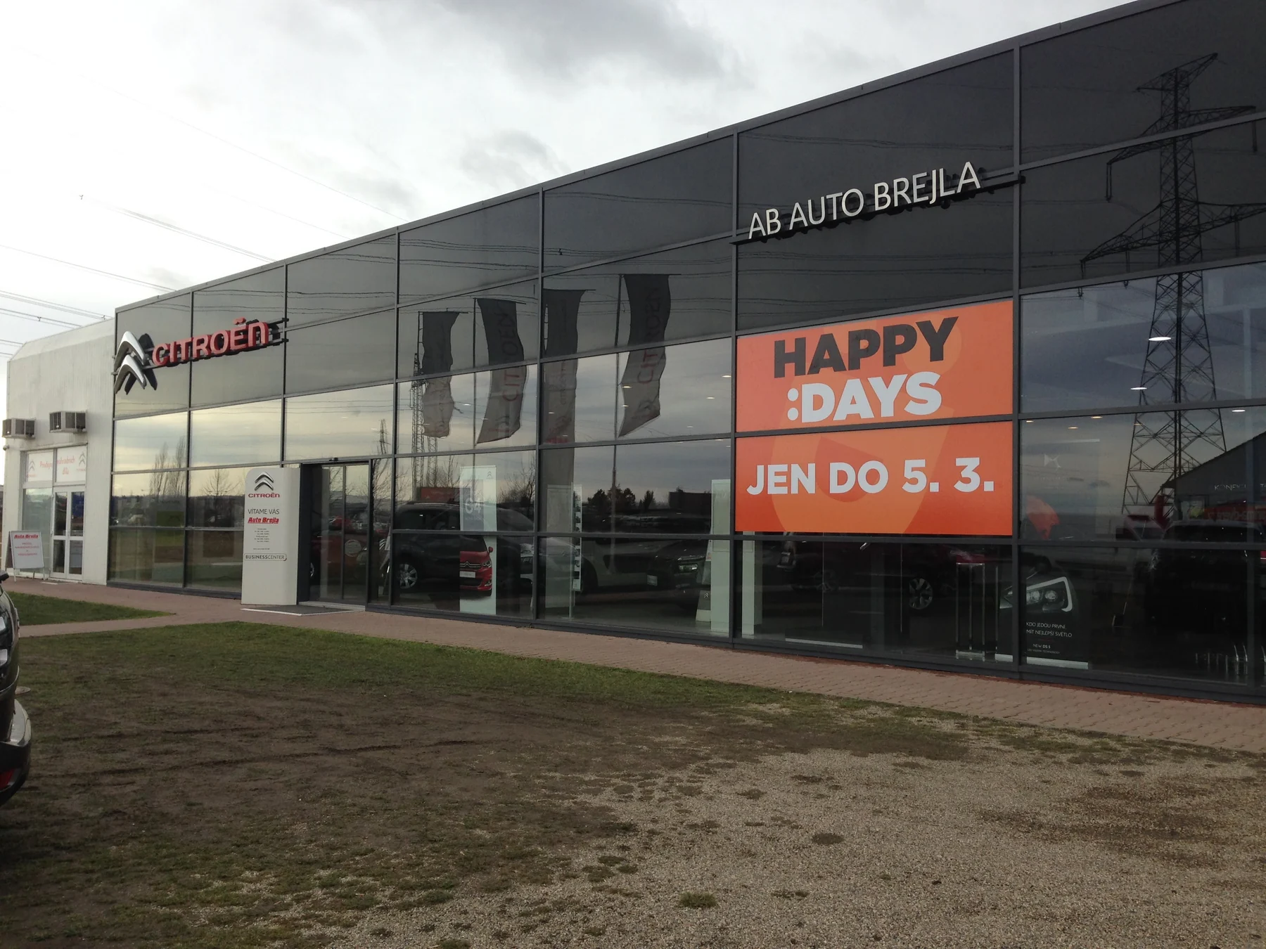 Budova autosalonu s oranžovým polepem Happy Days