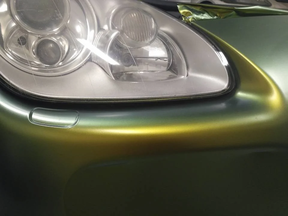 Detail zelenozlatého polepu Porsche Cayenne kolem předního světla