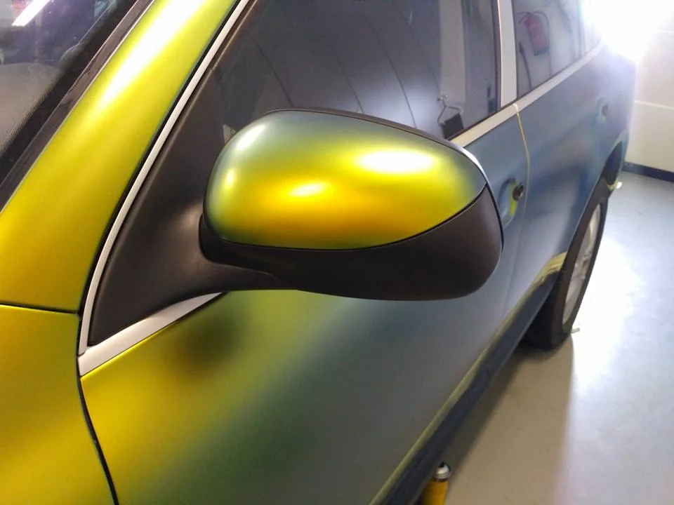 Detail zrcátka a předních dveří Porsche Cayenne se zlatými a zelenými odlesky polepu