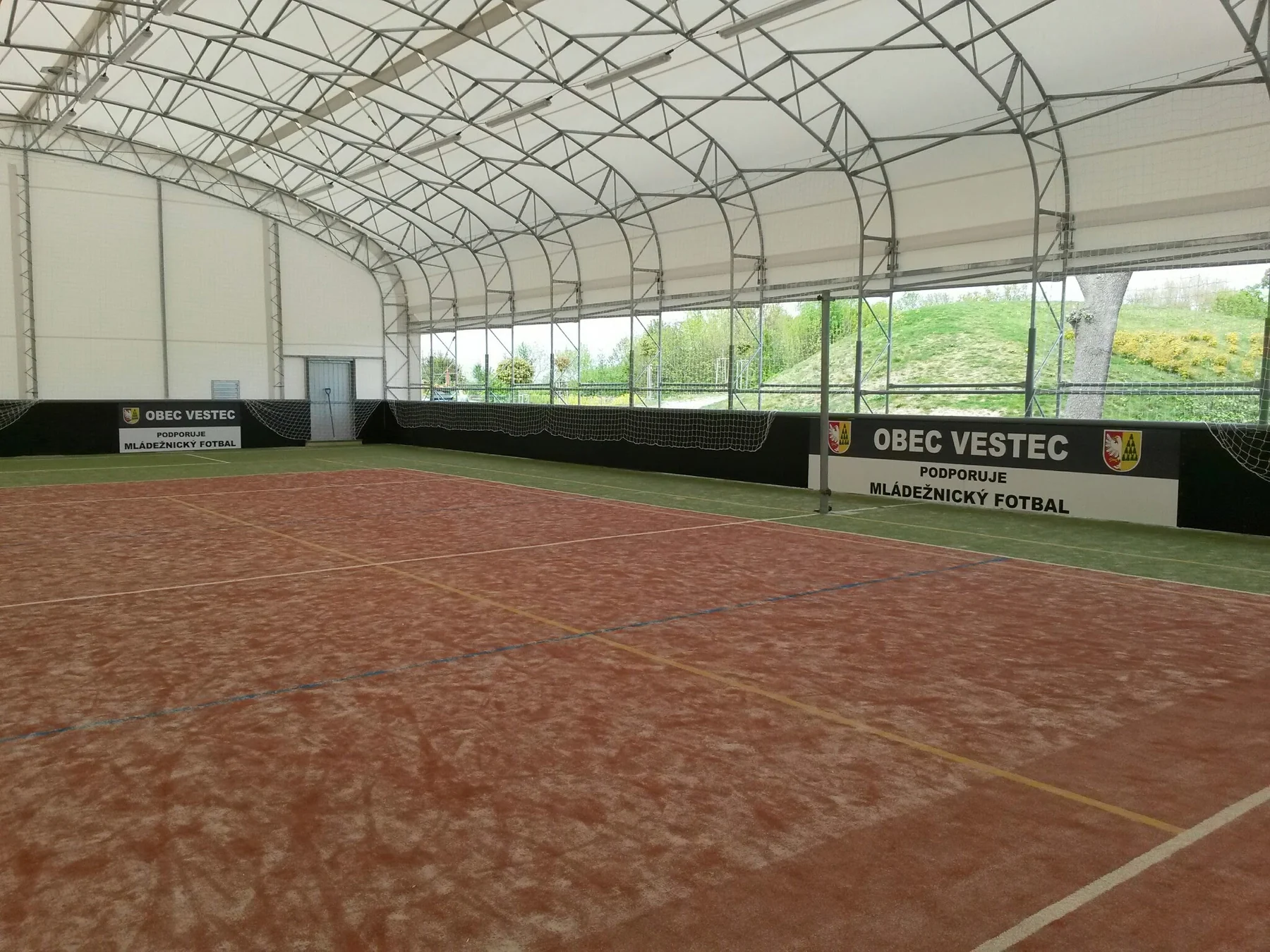 Reklamní panely rozmístěné kolem kryté sportovní plochy