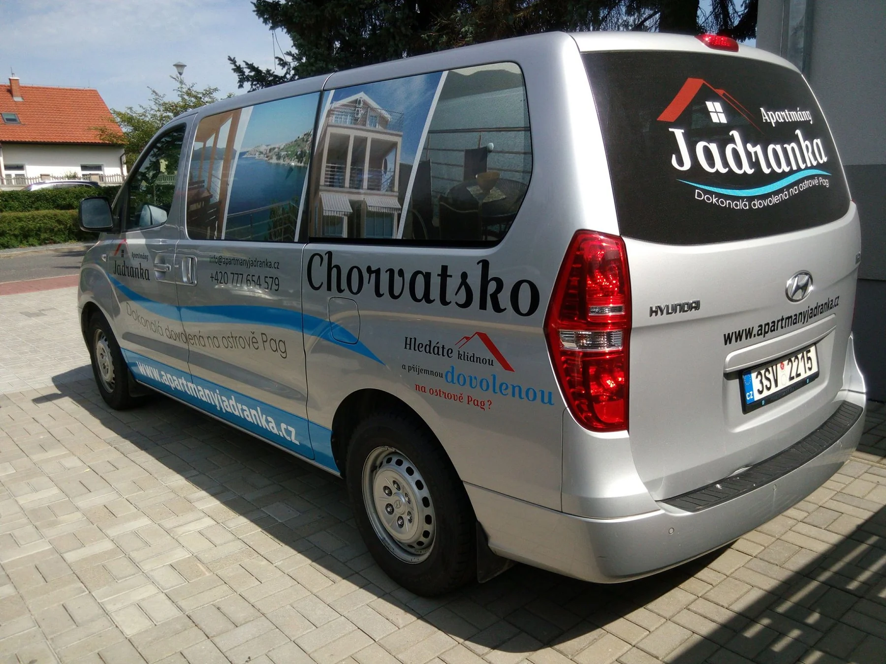 Dodávka Apartmány Jadranka z druhého zadního rohu s grafikou na boku a zadním skle