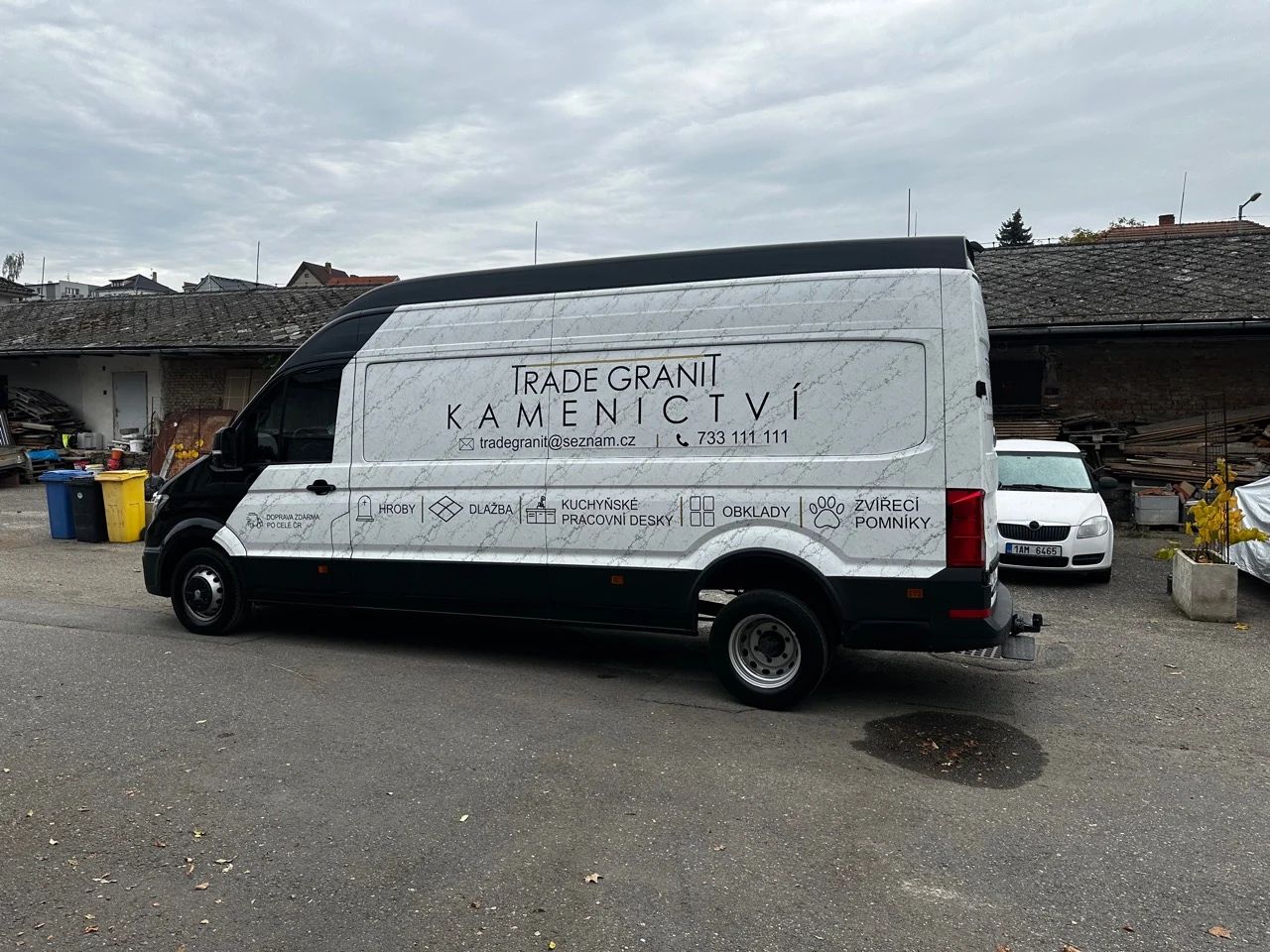 Boční pohled na Volkswagen Crafter s reklamním polepem Trade Granit, mramorovým motivem a přehledem kamenických služeb