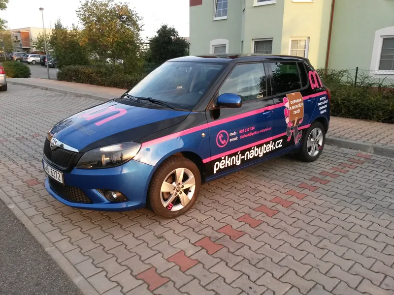 Modrá Škoda Fabia s reklamním polepem Pěkný nábytek zepředu a z boku