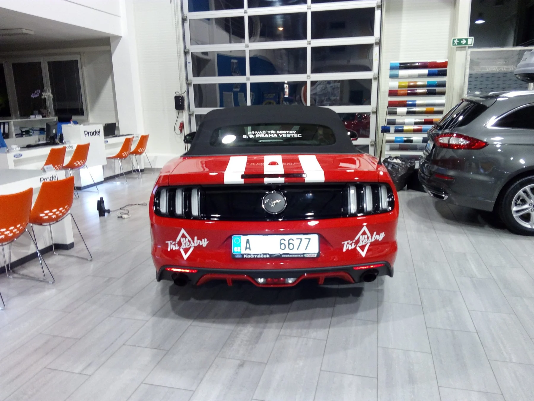 Přímý pohled na zadní část Mustangu s reklamou Tři sestry