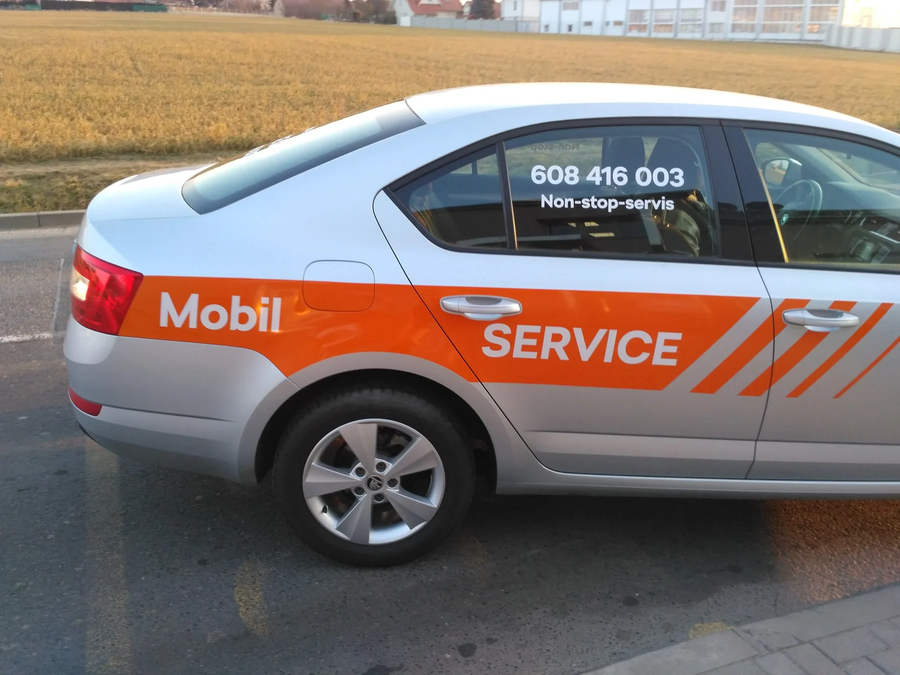 Detail oranžového nápisu Mobil Service na boku servisního vozu AD AUTO Praha