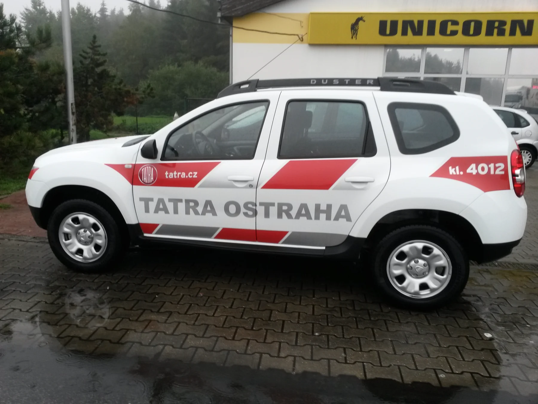 Boční pohled na bílý vůz TATRA OSTRAHA s červenými a šedými šikmými plochami