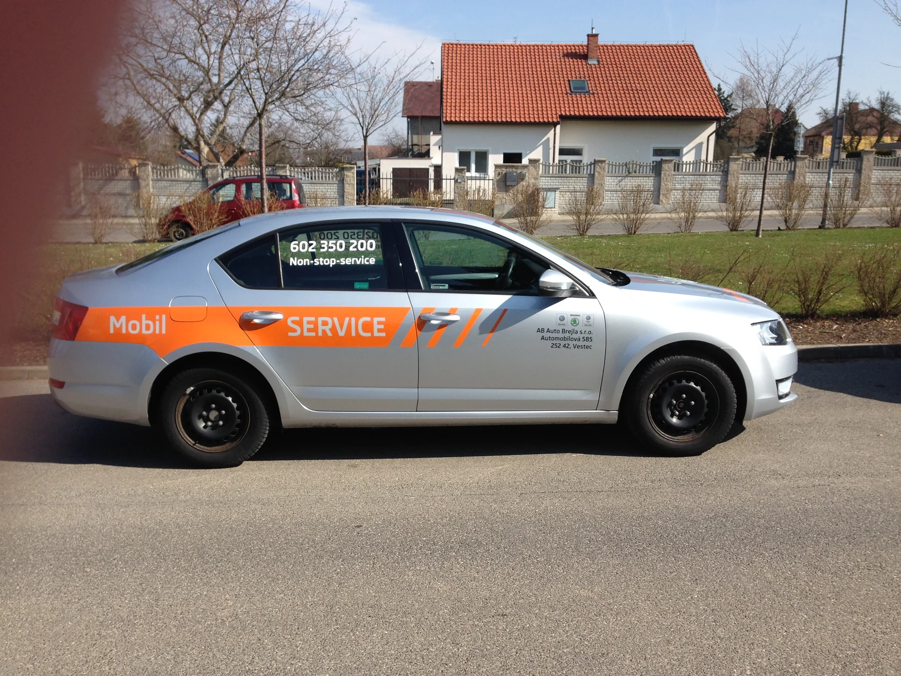 Boční pohled na stříbrný servisní vůz s oranžovým pásem Mobil Service