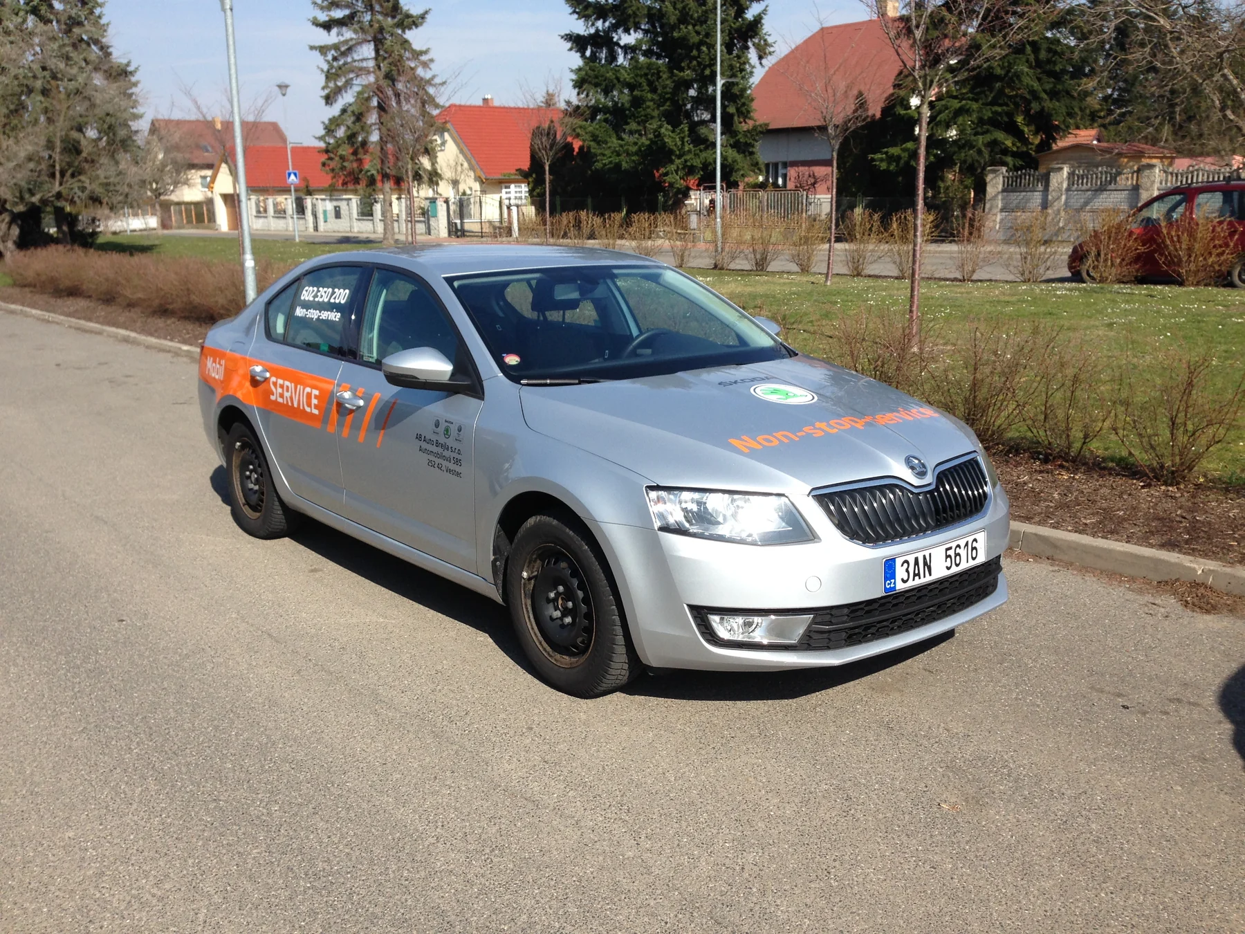 Stříbrný servisní vůz Auto Brejla s oranžovým polepem zepředu a z boku