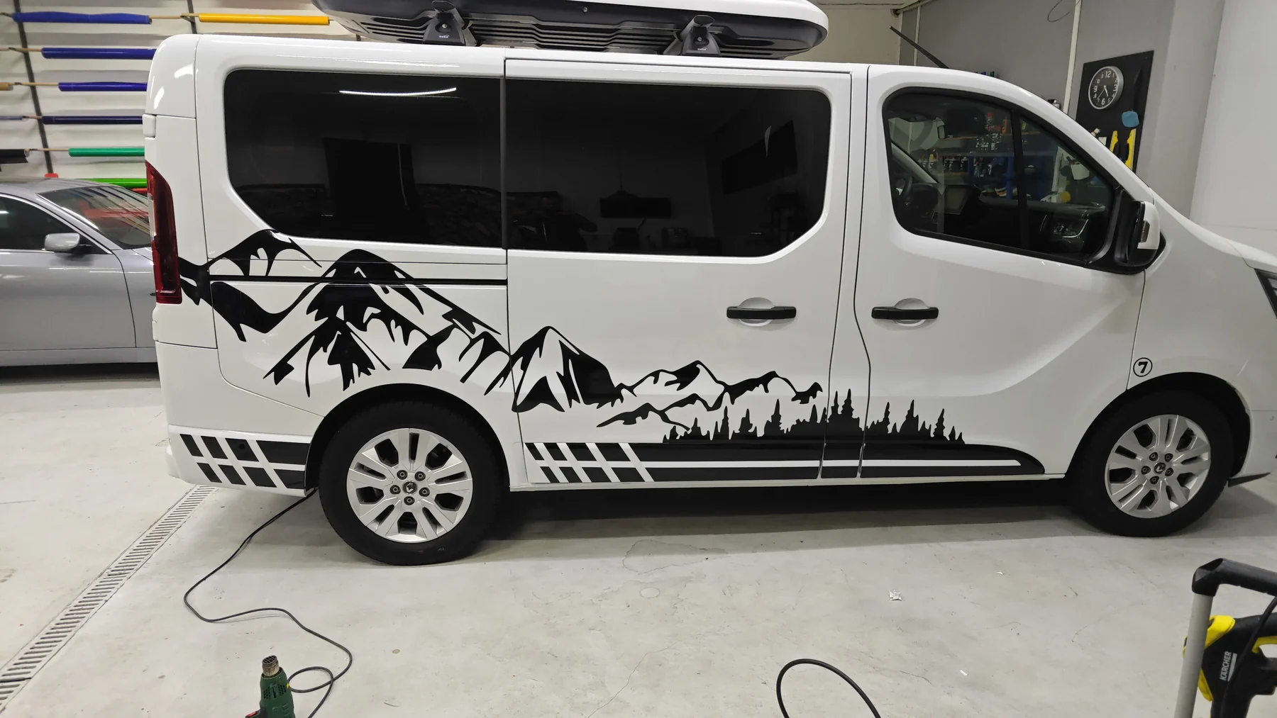 Bílý Renault Trafic s černým horským panoramatem na boku v dílně