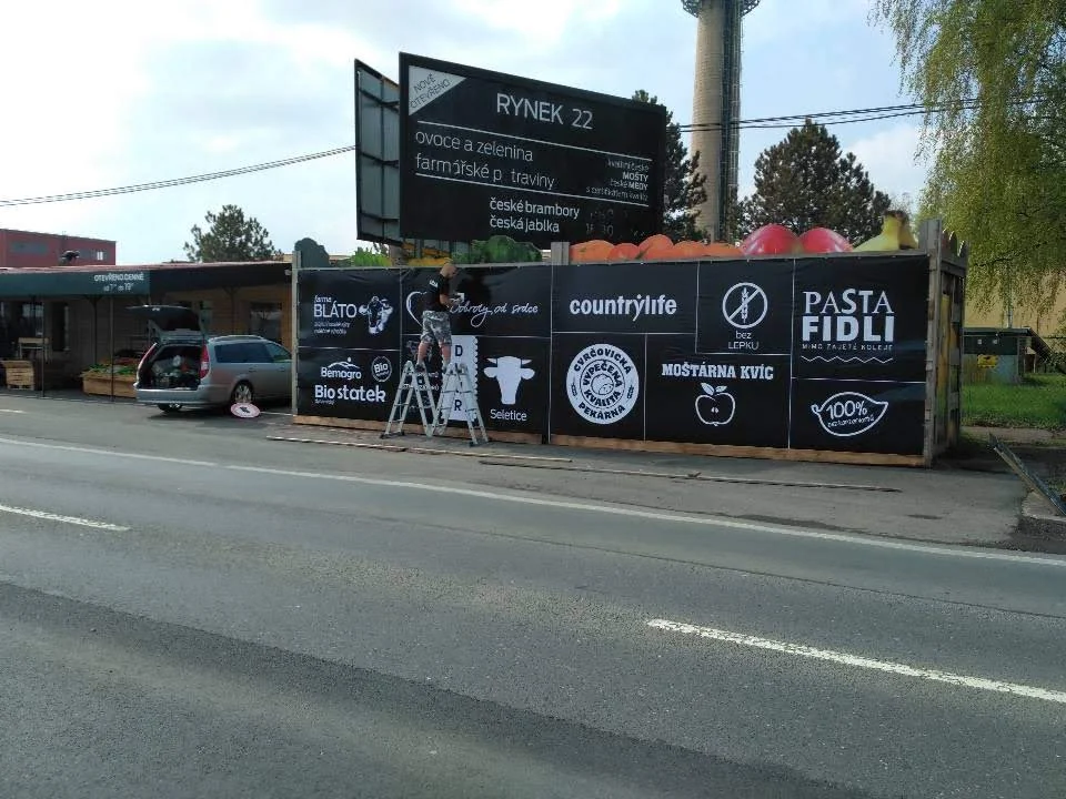 Prodejní místo Rynek 22 s černými panely a bílými logy během instalace