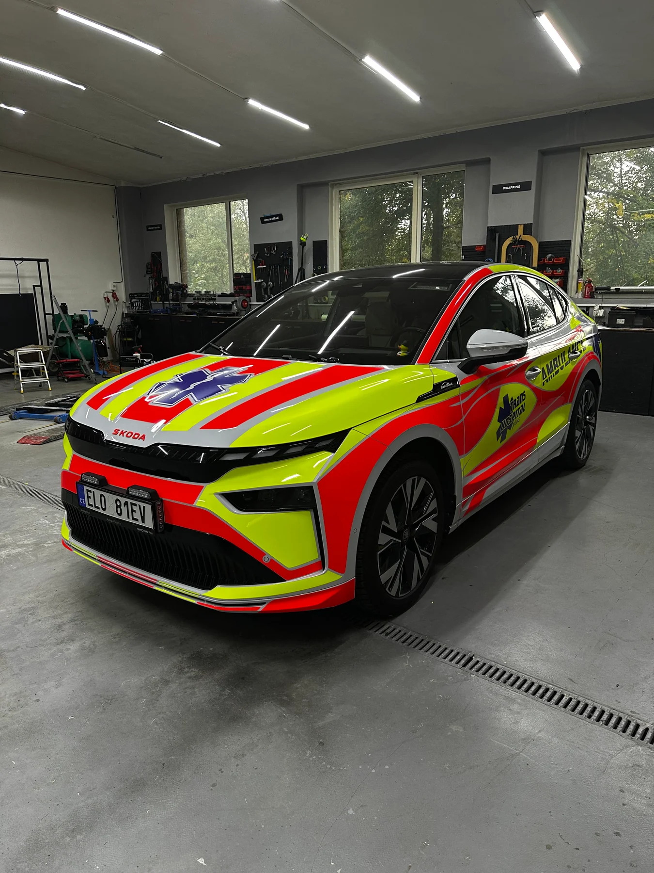 Škoda Enyaq Coupé pro Trans Hospital Plus se žlutočerveným polepem, pohled zepředu z levé strany
