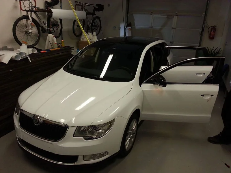 Bílý Superb kombi s černou střechou a zrcátky v dílně