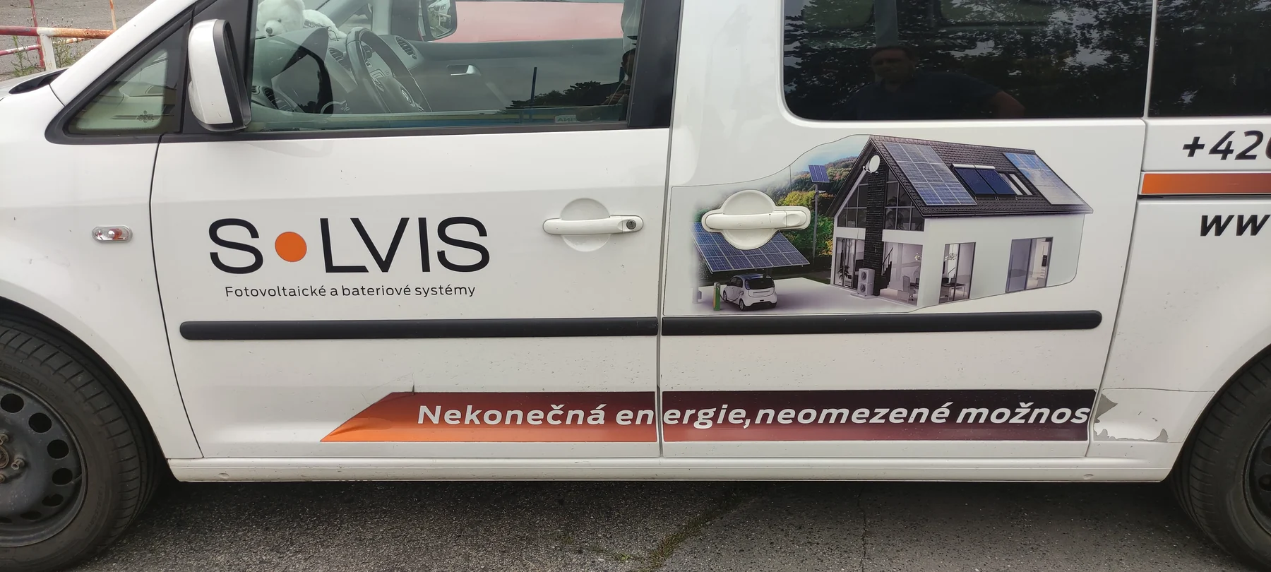 Boční dveře bílého Volkswagenu Caddy s reklamním polepem SOLVIS