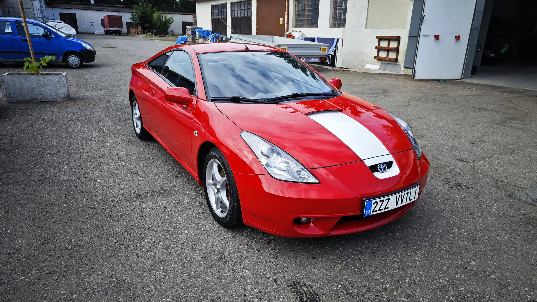 Červená Toyota Celica s bílým sportovním pruhem na kapotě