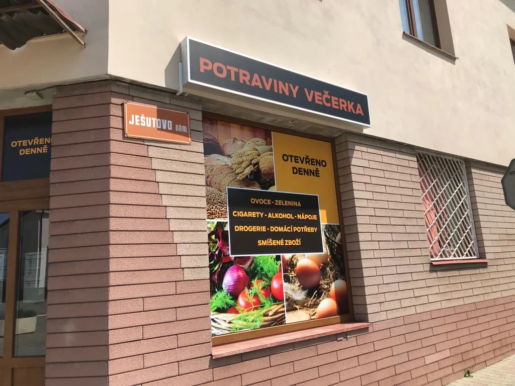 Výloha prodejny potravin s fotografickým polepem a horním nápisem Potraviny večerka