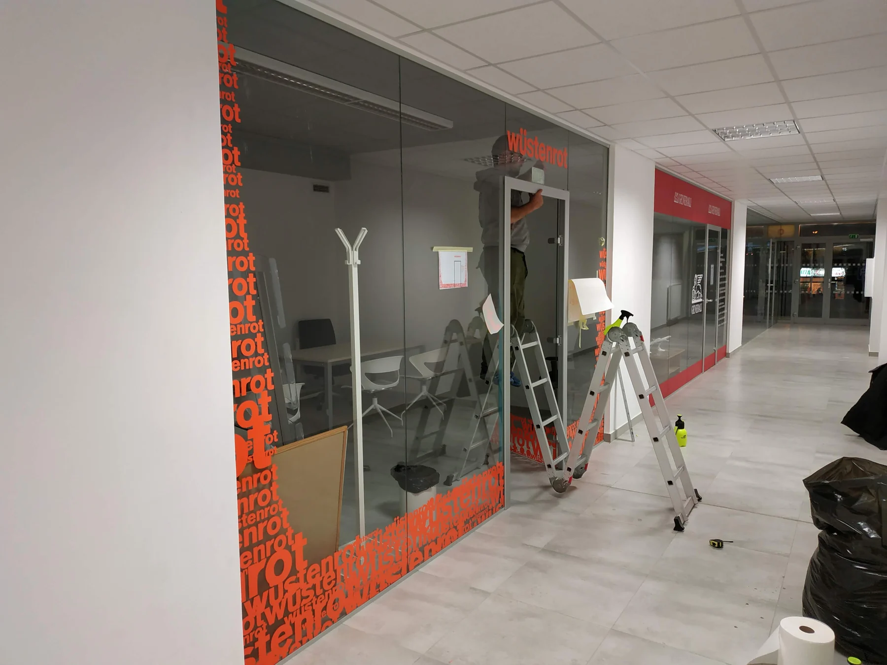 Prosklené čelo kanceláře při dokončování oranžové grafiky Wüstenrot