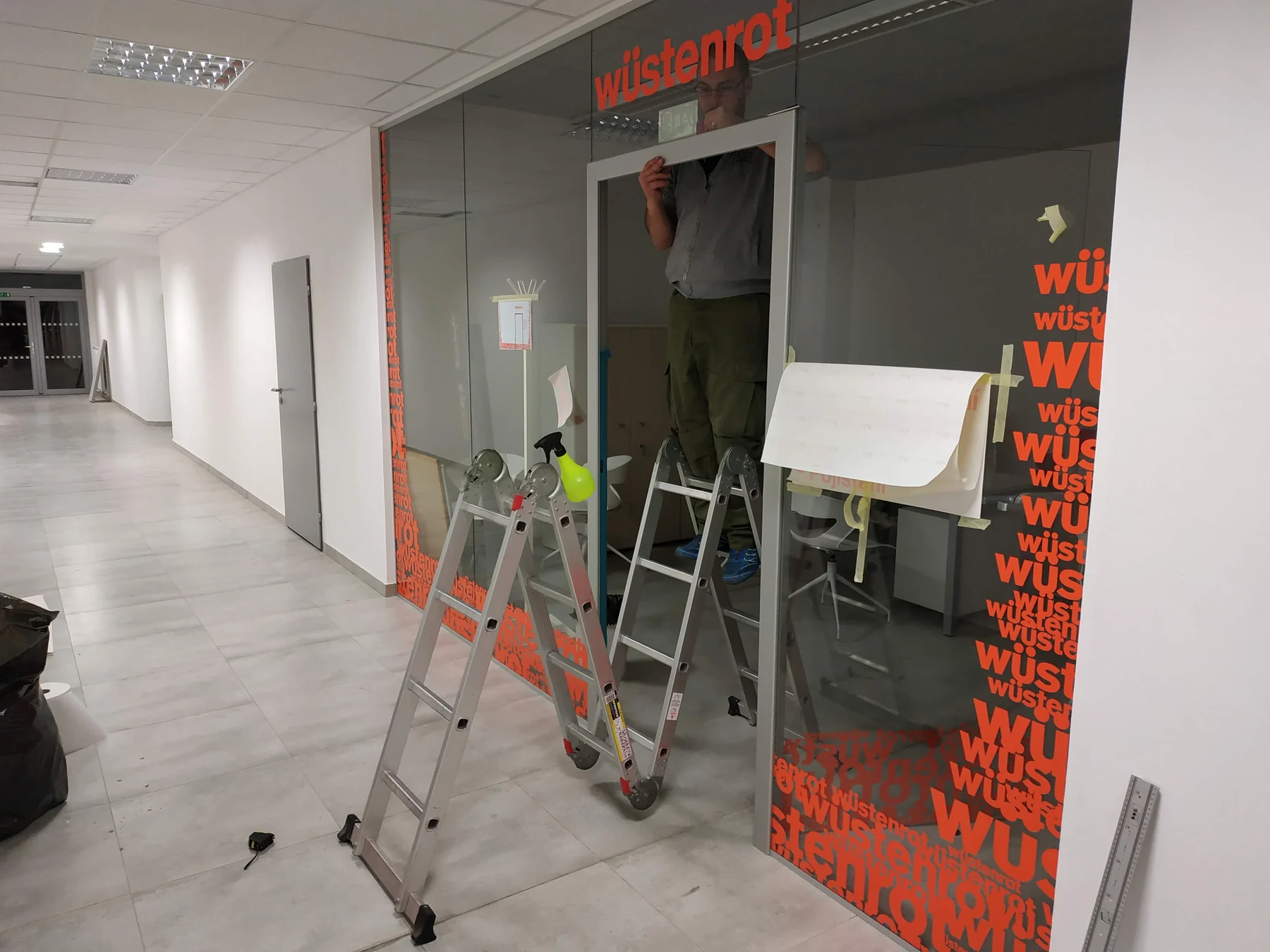Oranžová grafika a nápisy na prosklené kanceláři při dokončování